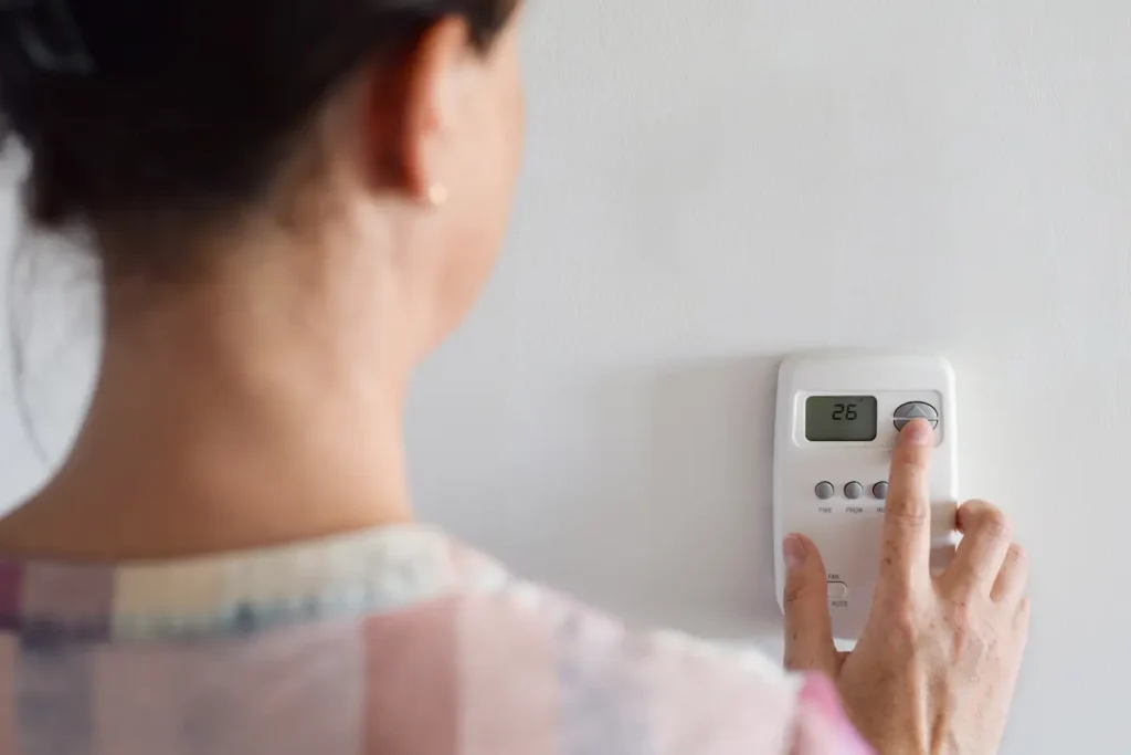 Woman adjusting thermostat temperature
