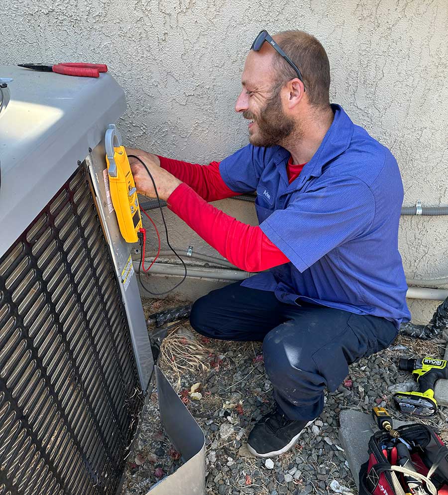 Advanced HVAC technician testing an open AC condenser with a digital meter during AC repair