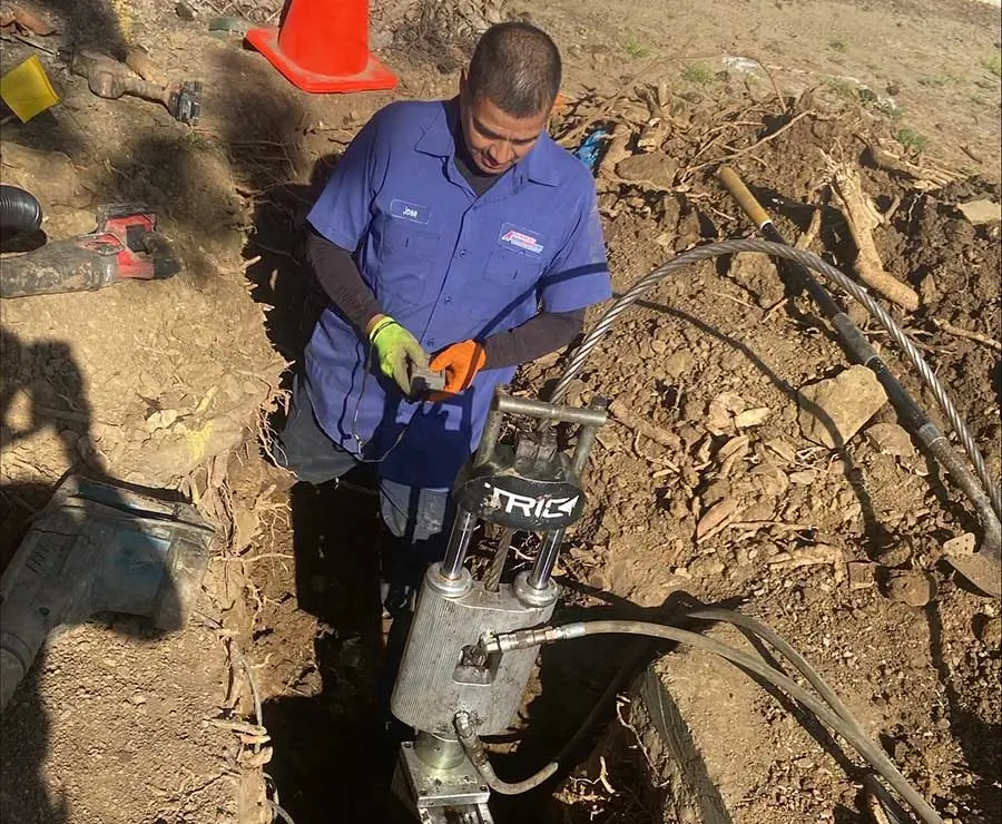 Commercial plumber servicing underground piping with specialized equipment inside a trench in Vacaville, CA