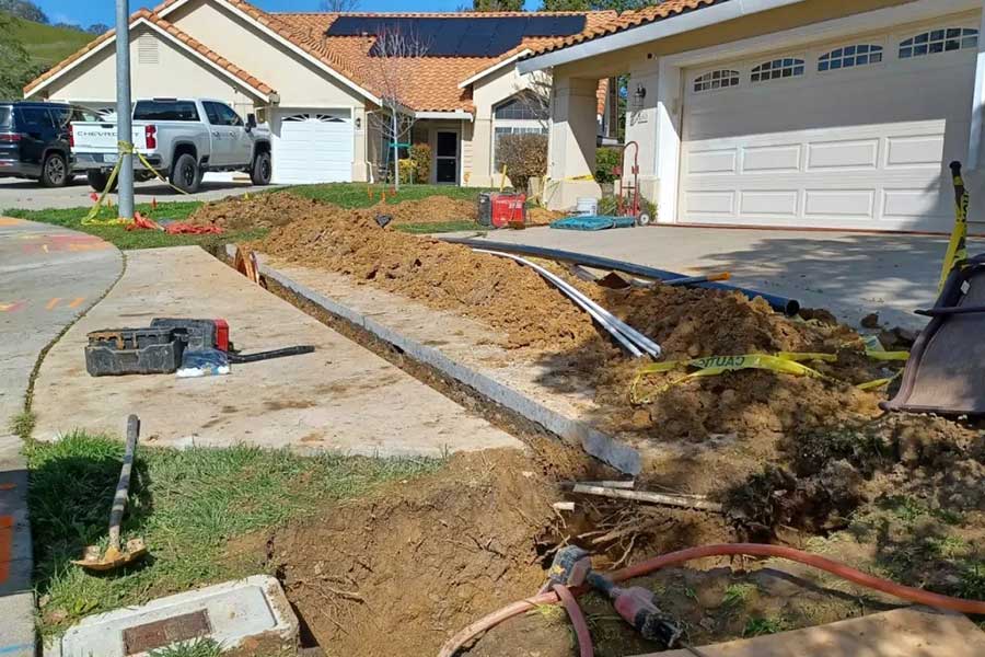 Residential main water line repair in Vacaville, CA with exposed piping in an excavated yard trench