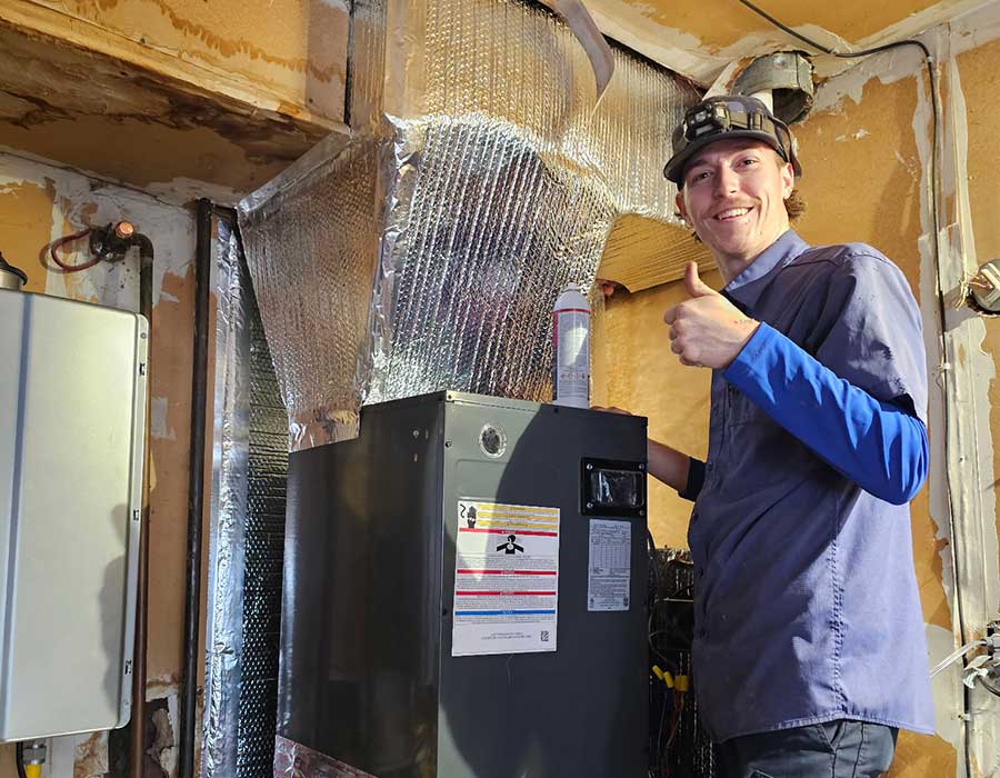 Technician completing a residential furnace installation with connected ductwork