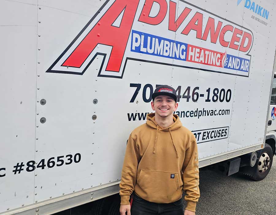 HVAC technician beside an Advanced Plumbing Heating and Air service vehicle for attic fan installation in Vacaville, CA