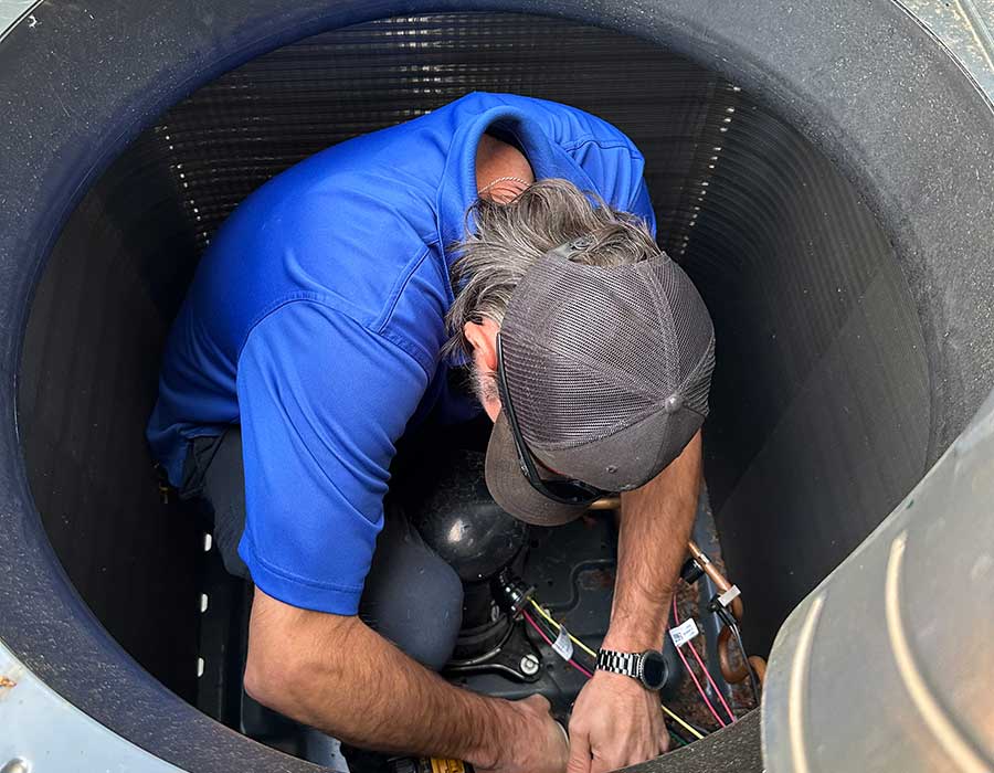 HVAC technician working inside outdoor cooling equipment for emergency repair service in Vacaville