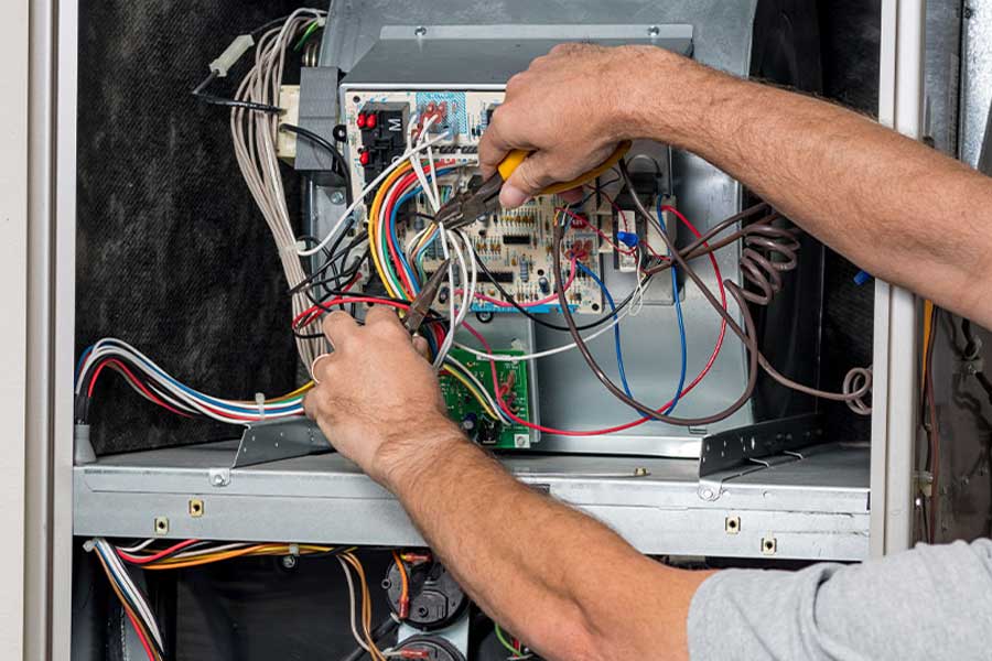 HVAC technician servicing furnace control board during a maintenance visit