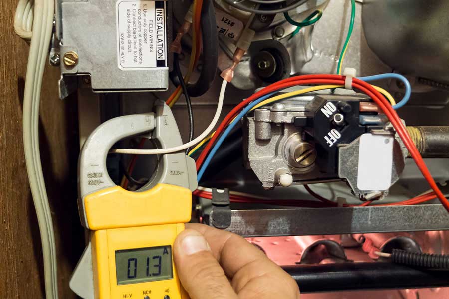 Technician checking furnace electrical readings with a digital clamp meter during maintenance in Vacaville, CA