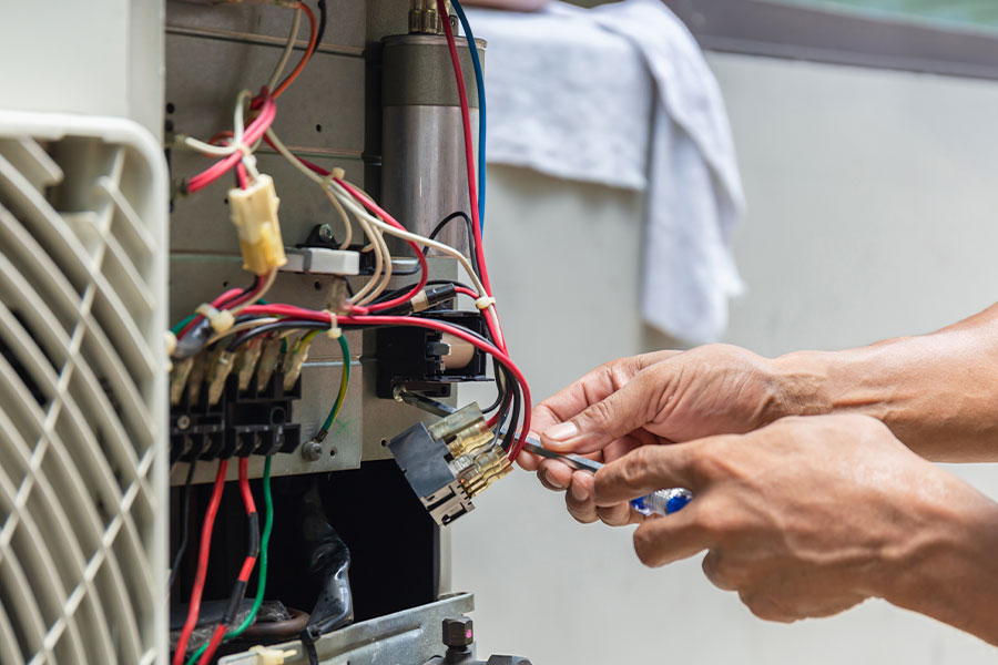 HVAC technician repairing electrical wiring and components inside a furnace unit in Vacaville, CA
