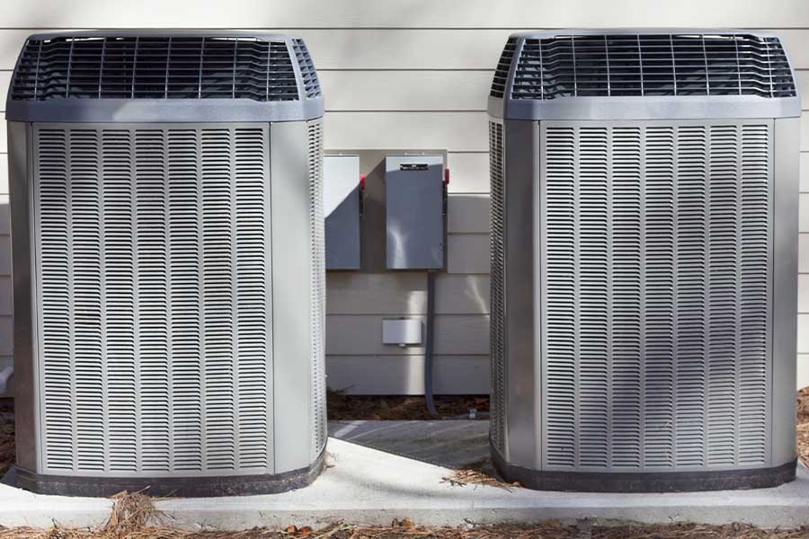 Two outdoor heat pump condenser units installed side by side beside a Vacaville home