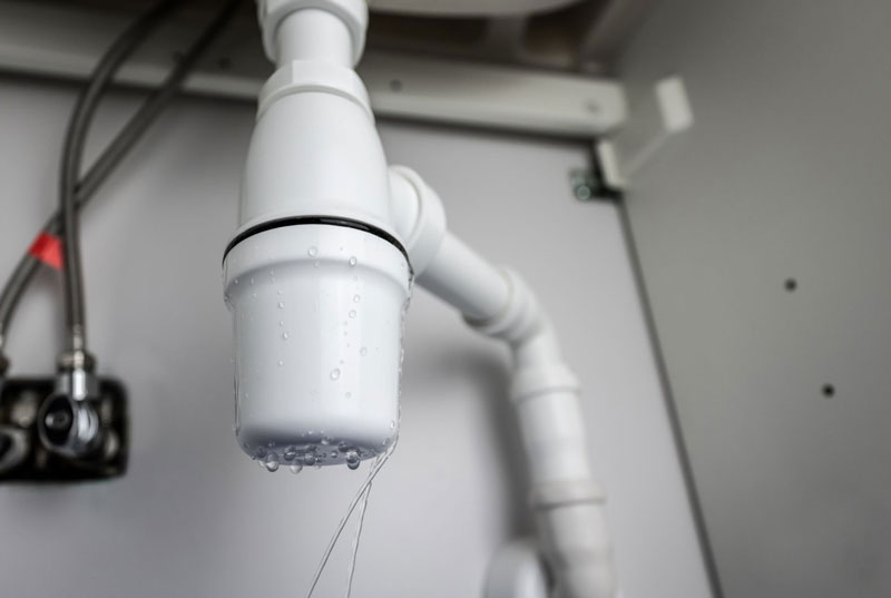 Kitchen sink drain leak inside an under-cabinet plumbing area